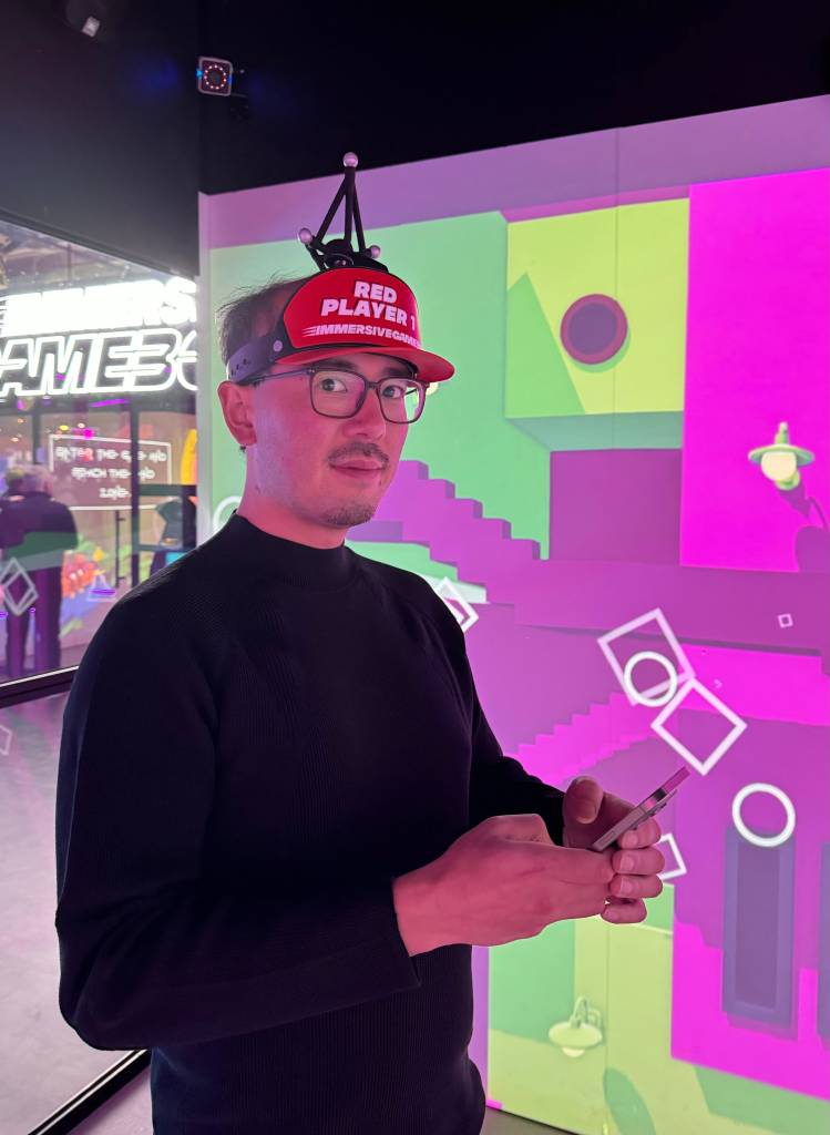 Adrian wears a red hat that says "Red Player 1" with some sticks and reflective white spheres on top