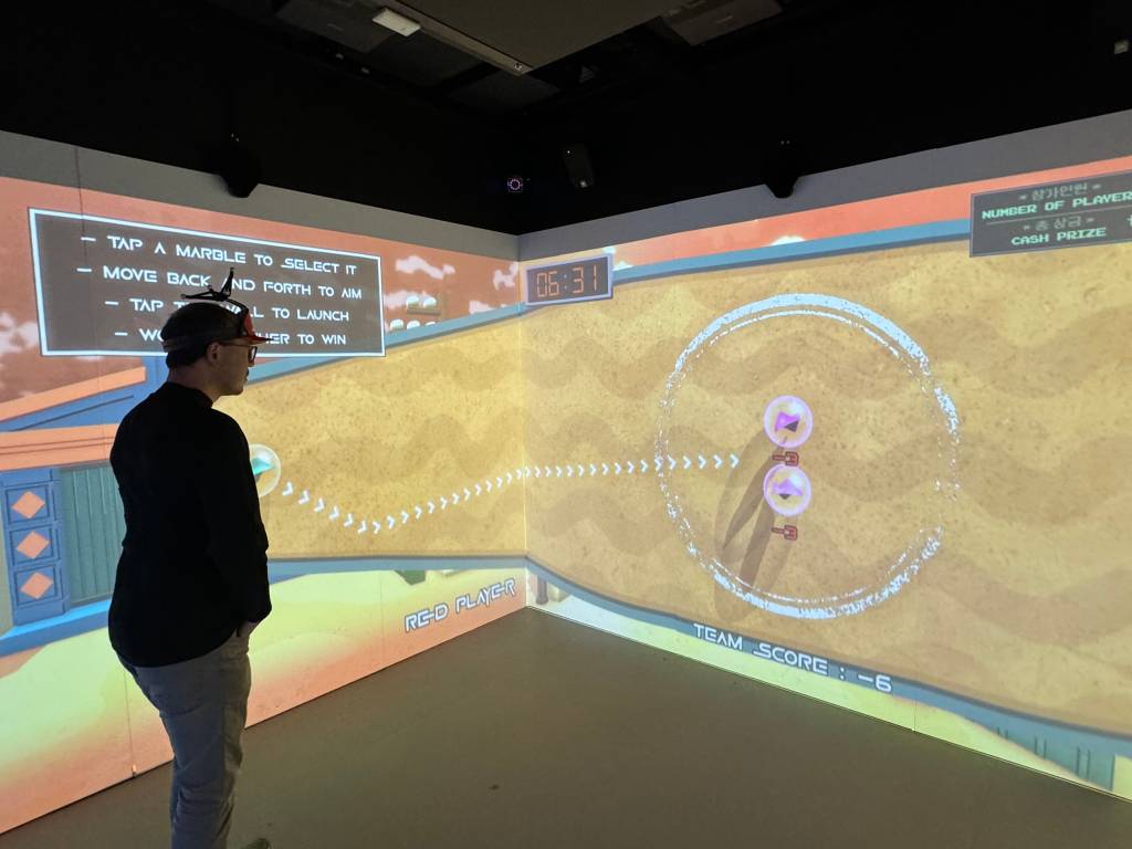Adrian looks at a screen where a directional arrow is pointed at two marbles, both labelled "-3"