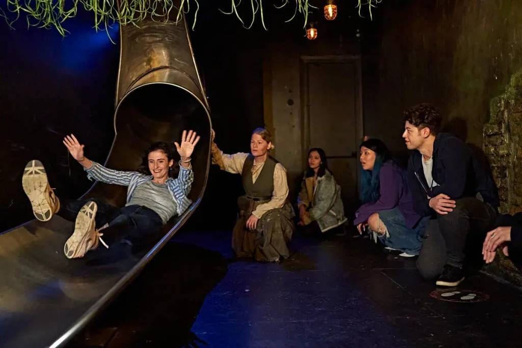 A woman comes down a metal slide, smiling