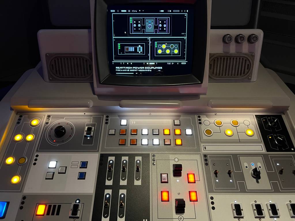 A computer screen with a pattern, and a big set of lit-up buttons underneath