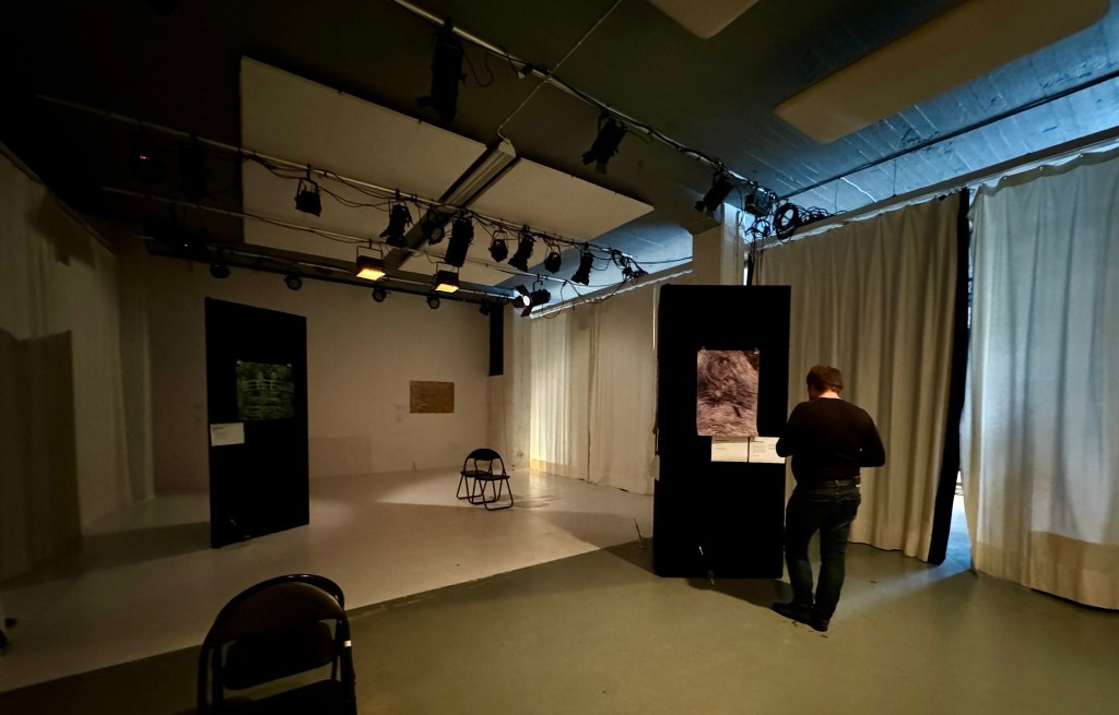 A person stands in front of a painting in an empty gallery