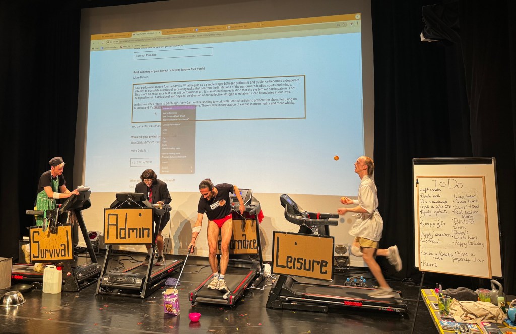 Four people on treadmills. Each treadmill has a sign: Survival, Admin, Performance, Leisure. The projection screen shows a grant application form. There's a whiteboard with a to-do list.