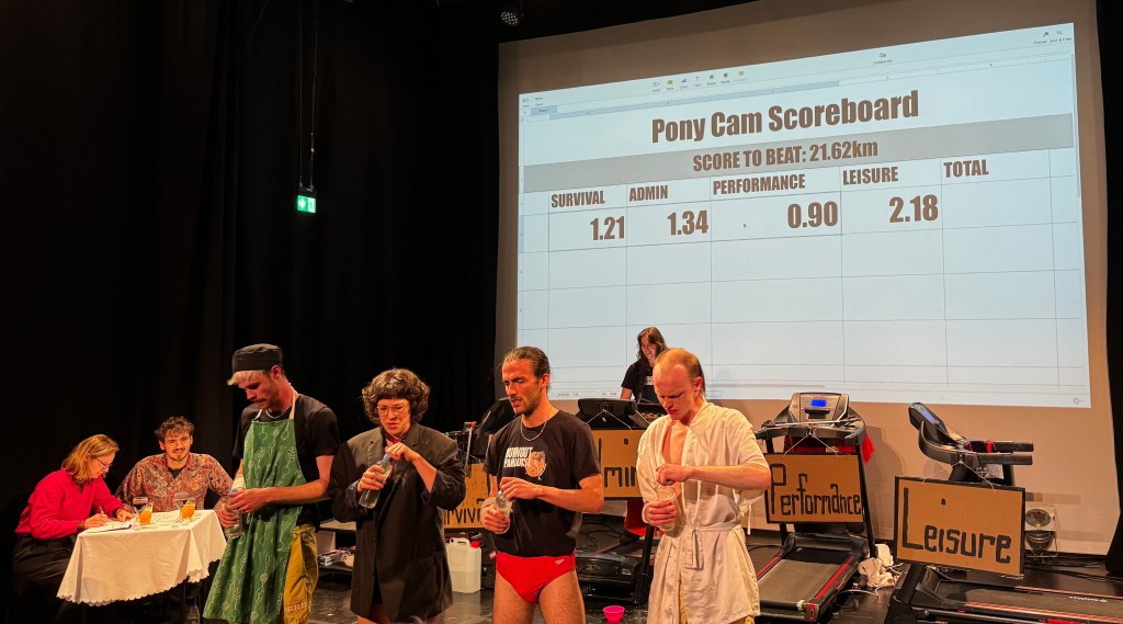 The four performers take a break. The scoreboard shows they've run 1.21km, 1.34km, 0.90km, and 2.18km after ten minutes, with a score to beat of 21.62km.