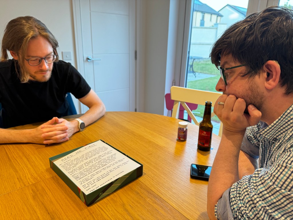 Two people sitting at a kitchen table reading a letter