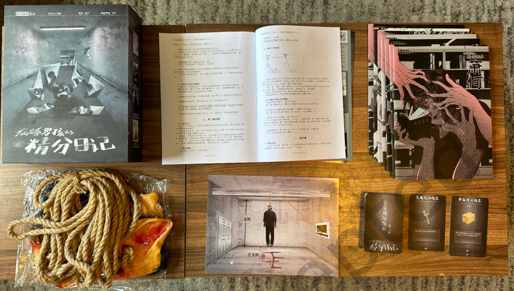 Photo of unboxed version of the game Plural Diary of the Yandere Boy, with lots of booklets and some props including cards, rope