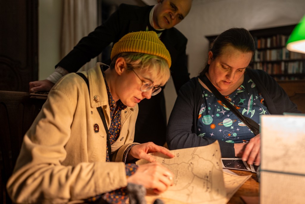 Two players and one actor examine a map