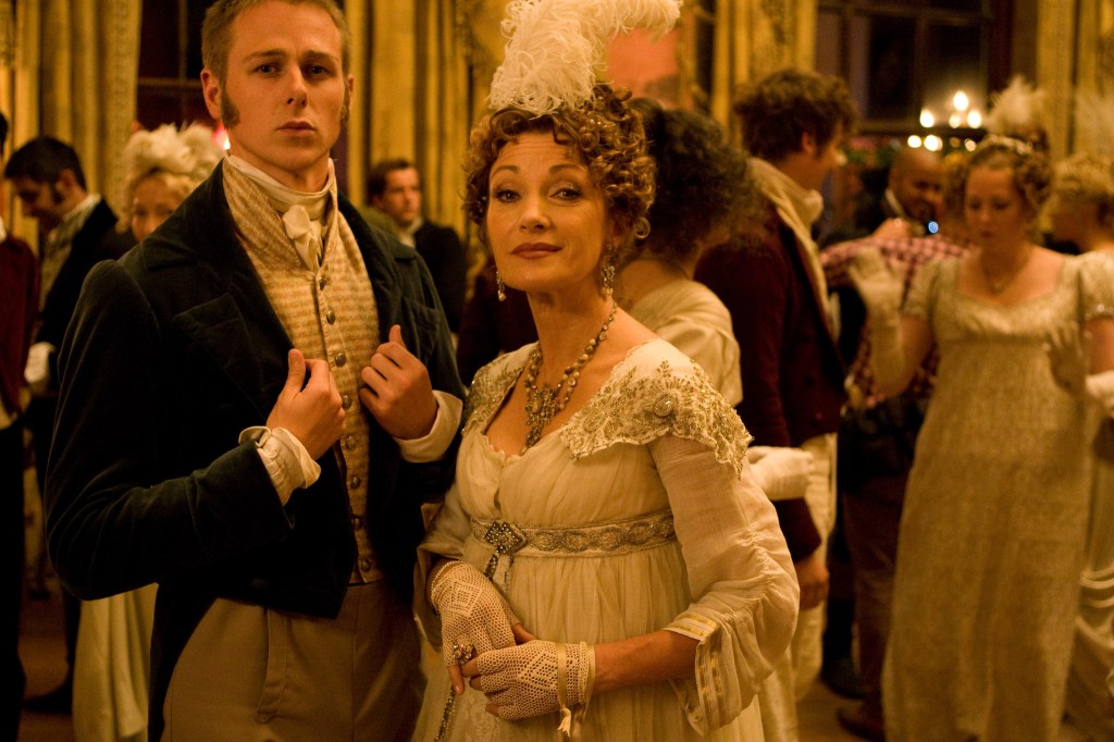 A man and woman in period costume in a crowded ballroom