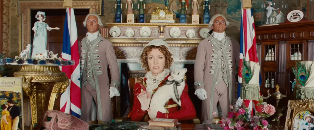 Mrs. Wattlesbrook in period costume, flanked by two footmen