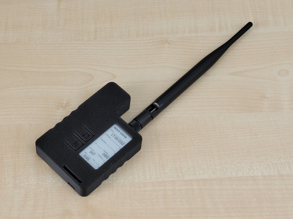 A black device with a vertical screen and long antenna