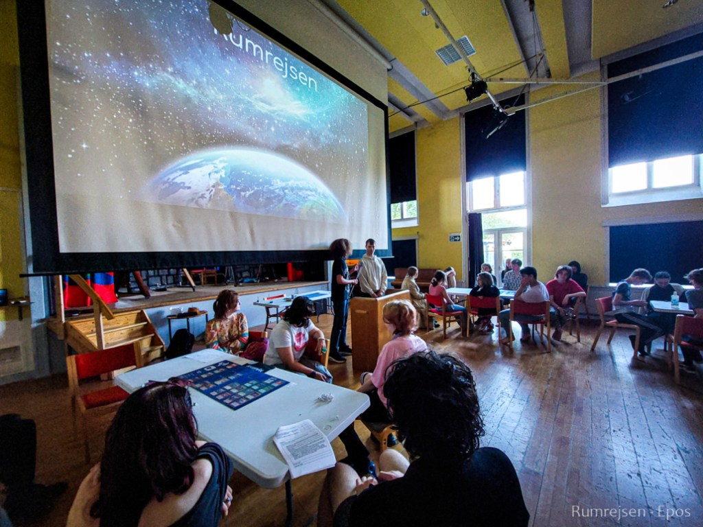 A school hall with students around a table below a projector showing Earth