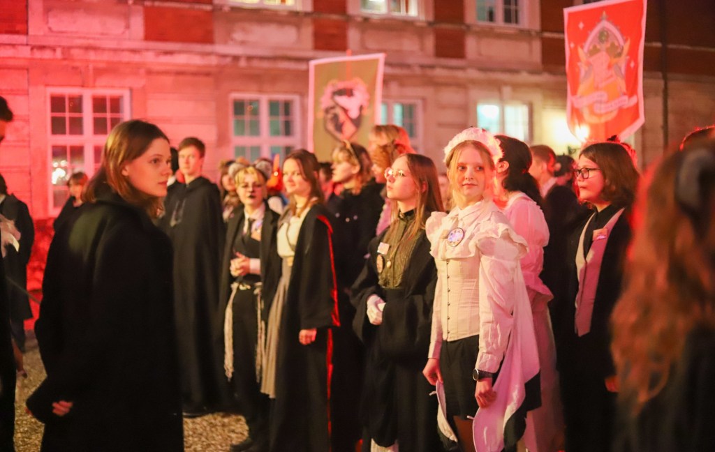 Students in robes lined up outside in front of banners