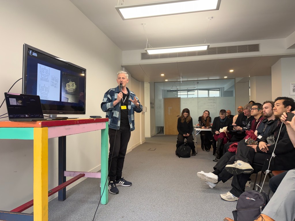 A man standing next to a TV screen presenting to an audience