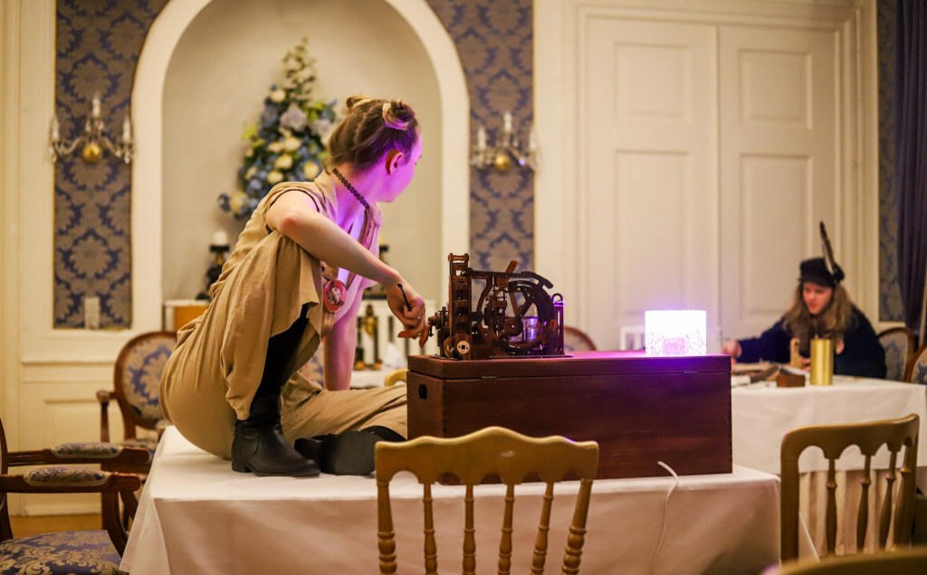 A person sitting on a table next to a steampunk-looking box