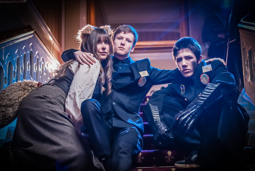 Three students sitting on a staircase, their arms around each other